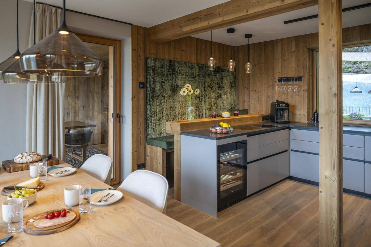 Geräumiger Wohn-Essbereich mit integrierter Küche, Holzwänden und modernen Geräten.