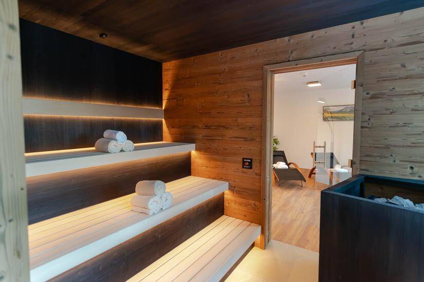 Moderne Sauna mit Holzverkleidung und indirekter Beleuchtung, Teil eines Wellnessbereichs.