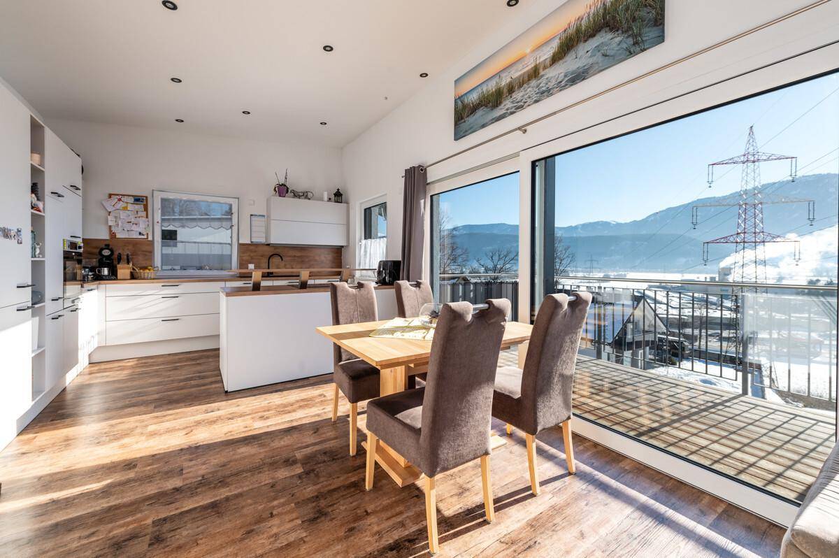 Offene Küche mit Essbereich, Holzboden und Zugang zum Balkon mit Bergsicht.