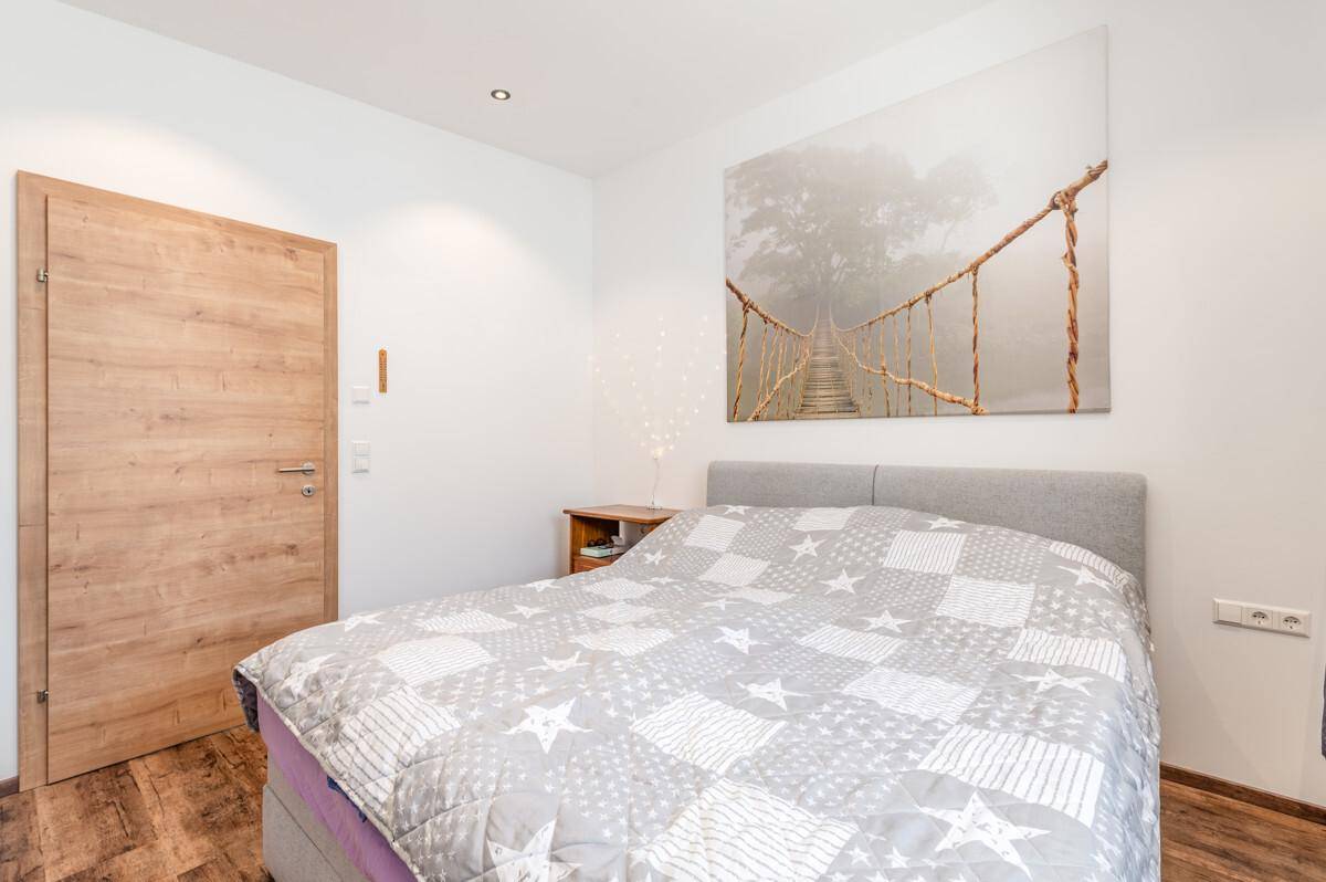 Ruhiges Schlafzimmer mit großem Bett, Holzboden und einer modernen Holztür.