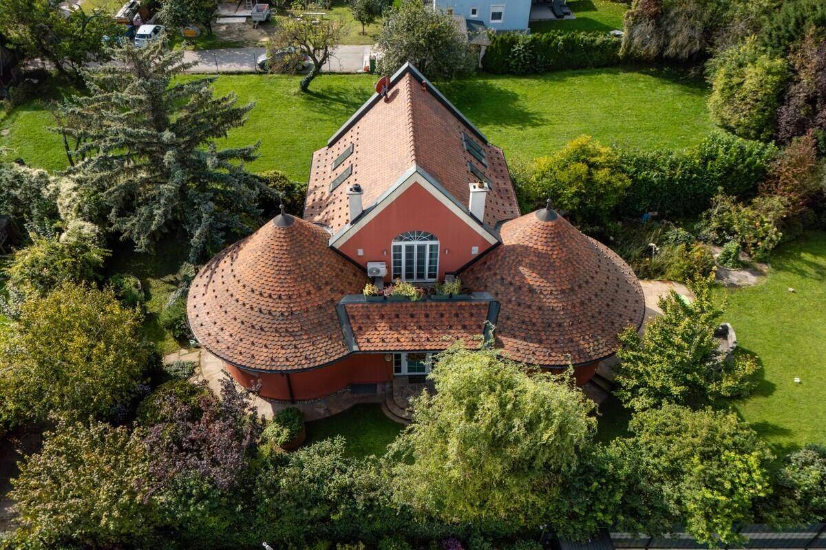 Außergewöhnliches Wohnhaus mit runden Dächern und gepflegtem Garten aus der Vogelperspektive.