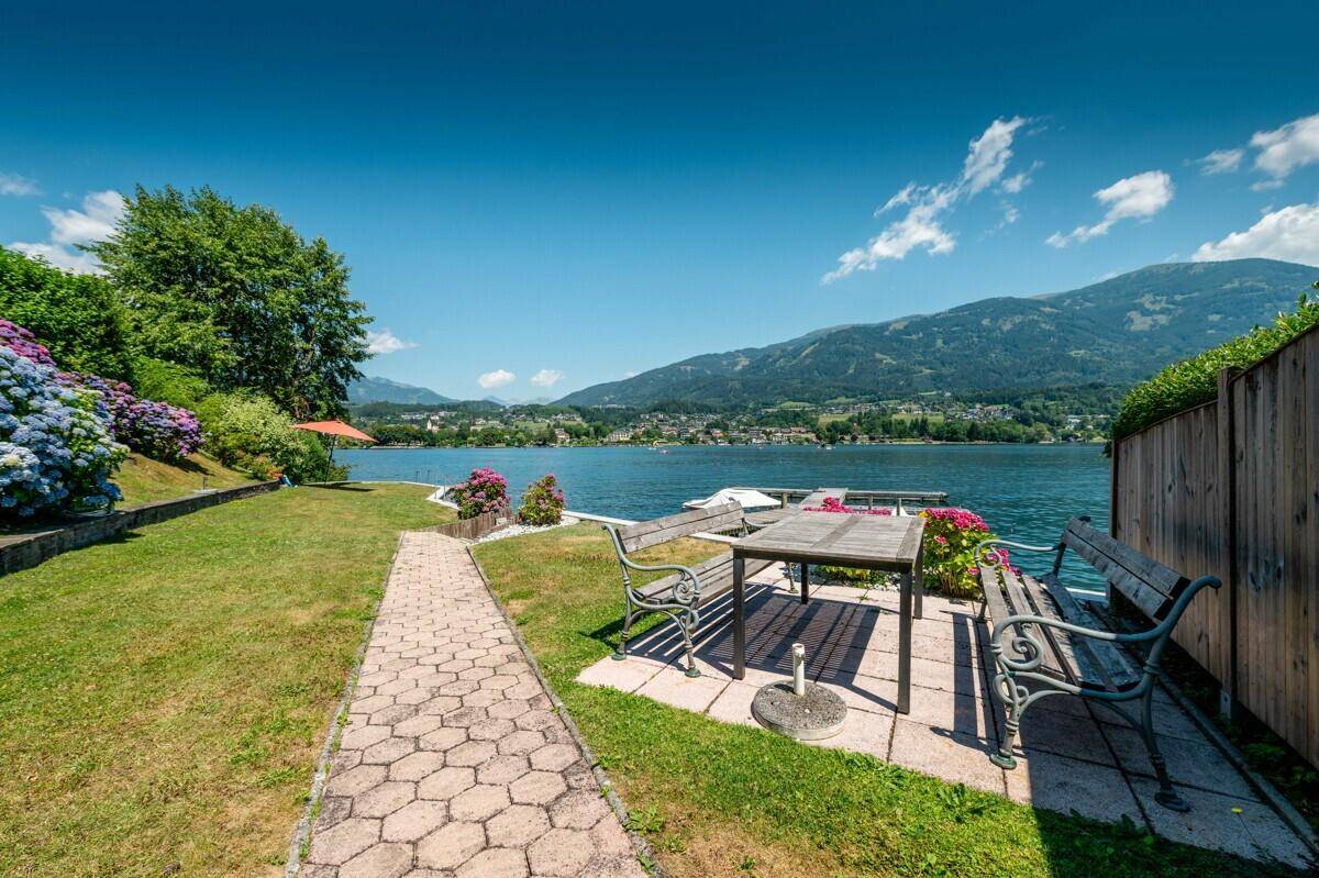 Idyllischer Gartenbereich mit Sitzgelegenheiten und weitem Blick über den See.