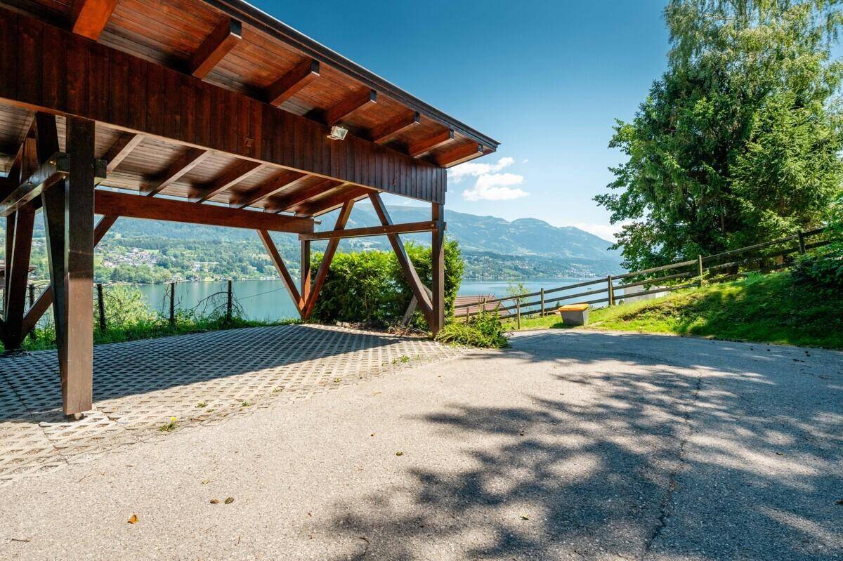 Holzcarport mit Seeblick und umgeben von grüner Landschaft.
