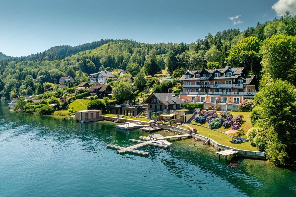 Gesamtaufnahme des luxuriösen Anwesens am See mit weitläufigen Gärten und Bootsanlegestellen.
