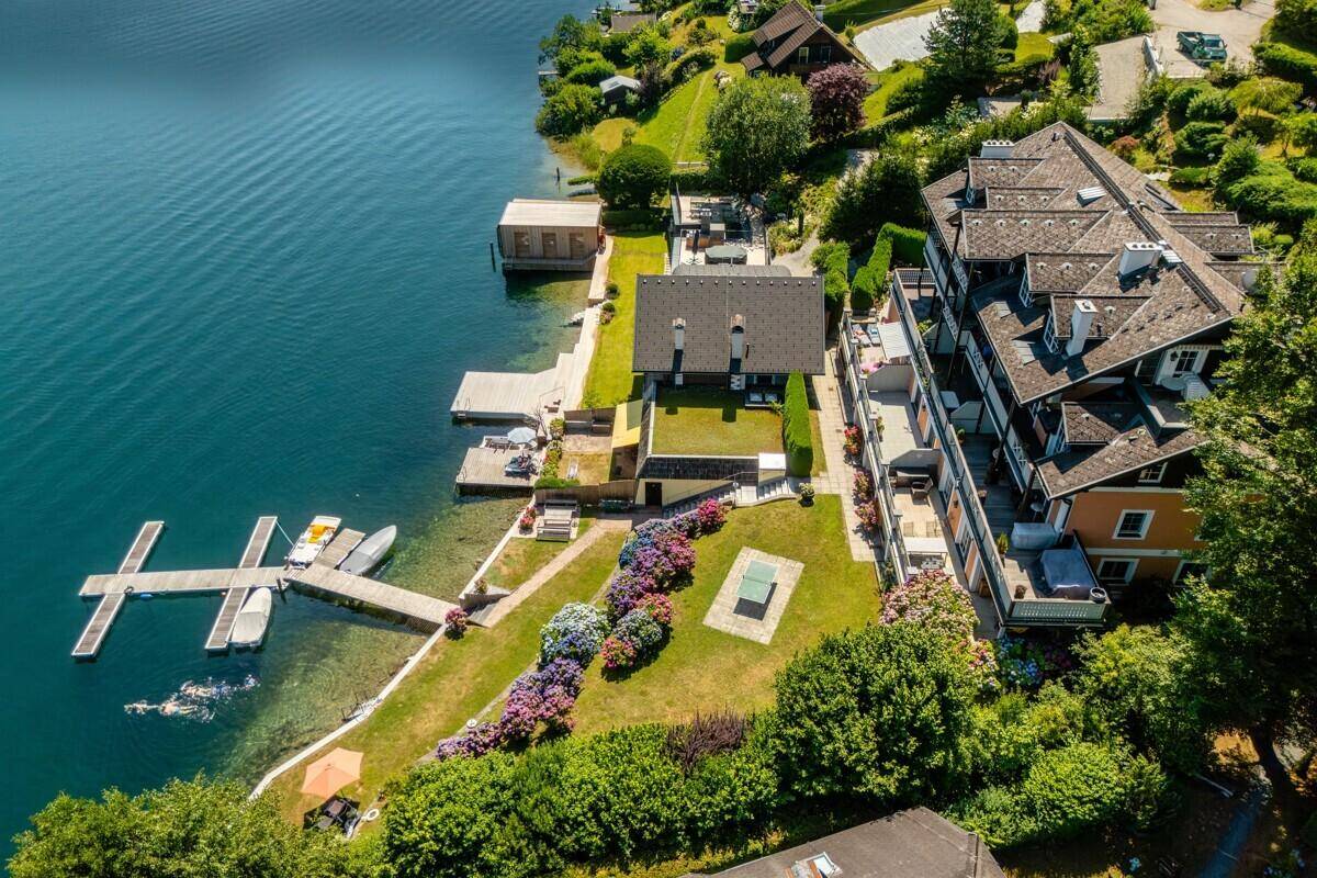 Vogelperspektive des Anwesens mit Garten, Tischtennisplatte und Bootsstegen am See.