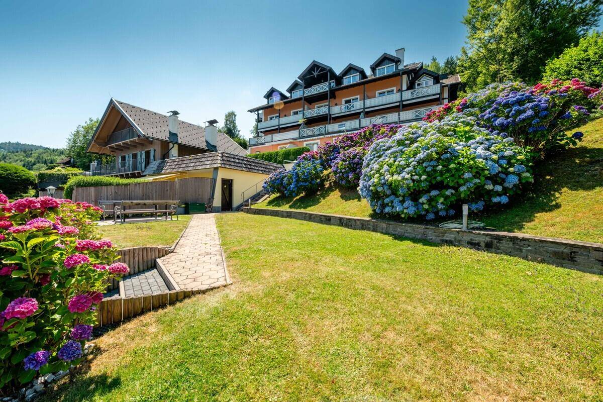 Weitläufiger Garten mit blühenden Hortensien und Blick auf das Hauptgebäude.
