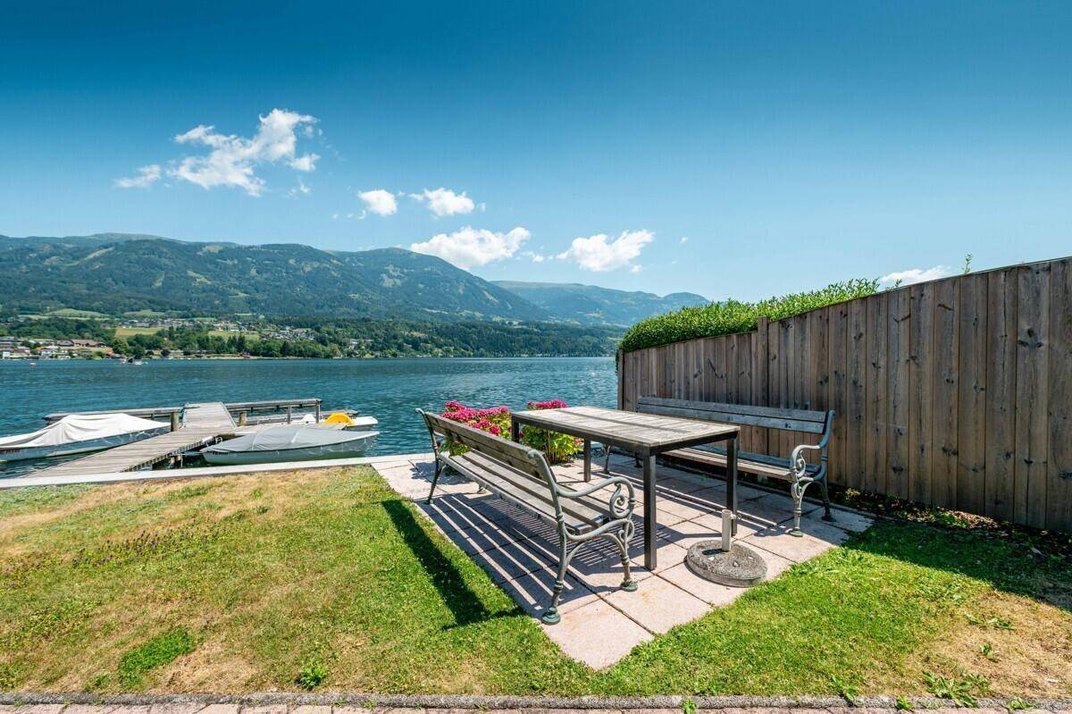 Gemütlicher Sitzbereich im Garten mit Esstisch und direktem Seeblick.