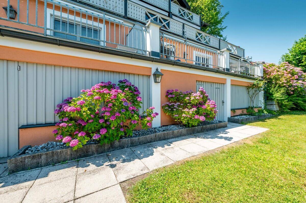 Fassade des Gebäudes mit Garagen und blühenden Hortensien im Vorgarten.