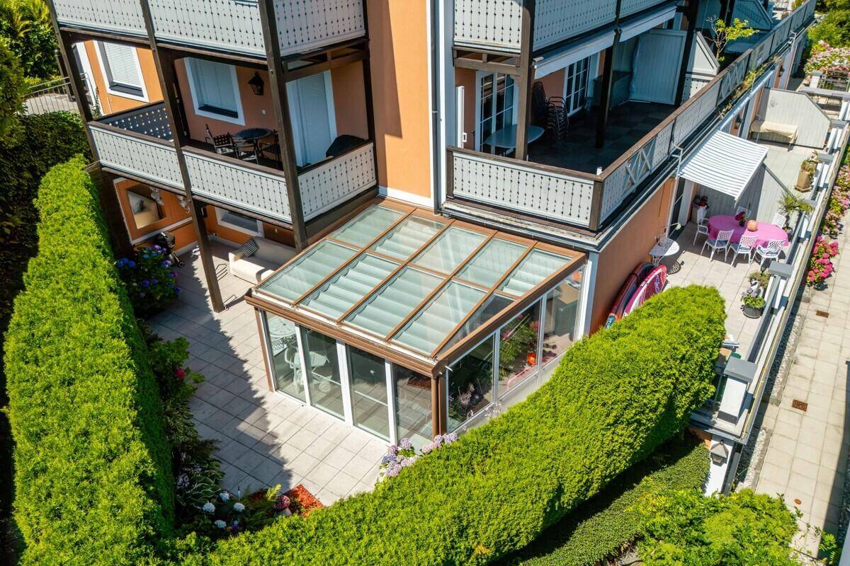 Wintergarten und angrenzende Terrasse, umgeben von hohen Hecken.