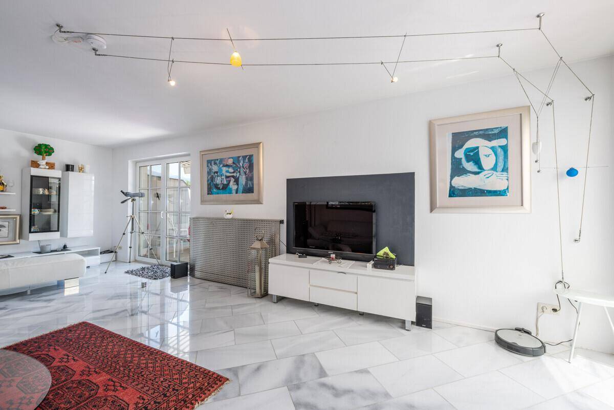 Modernes Wohnzimmer mit Marmorboden, großem Fernseher und minimalistischer Einrichtung.