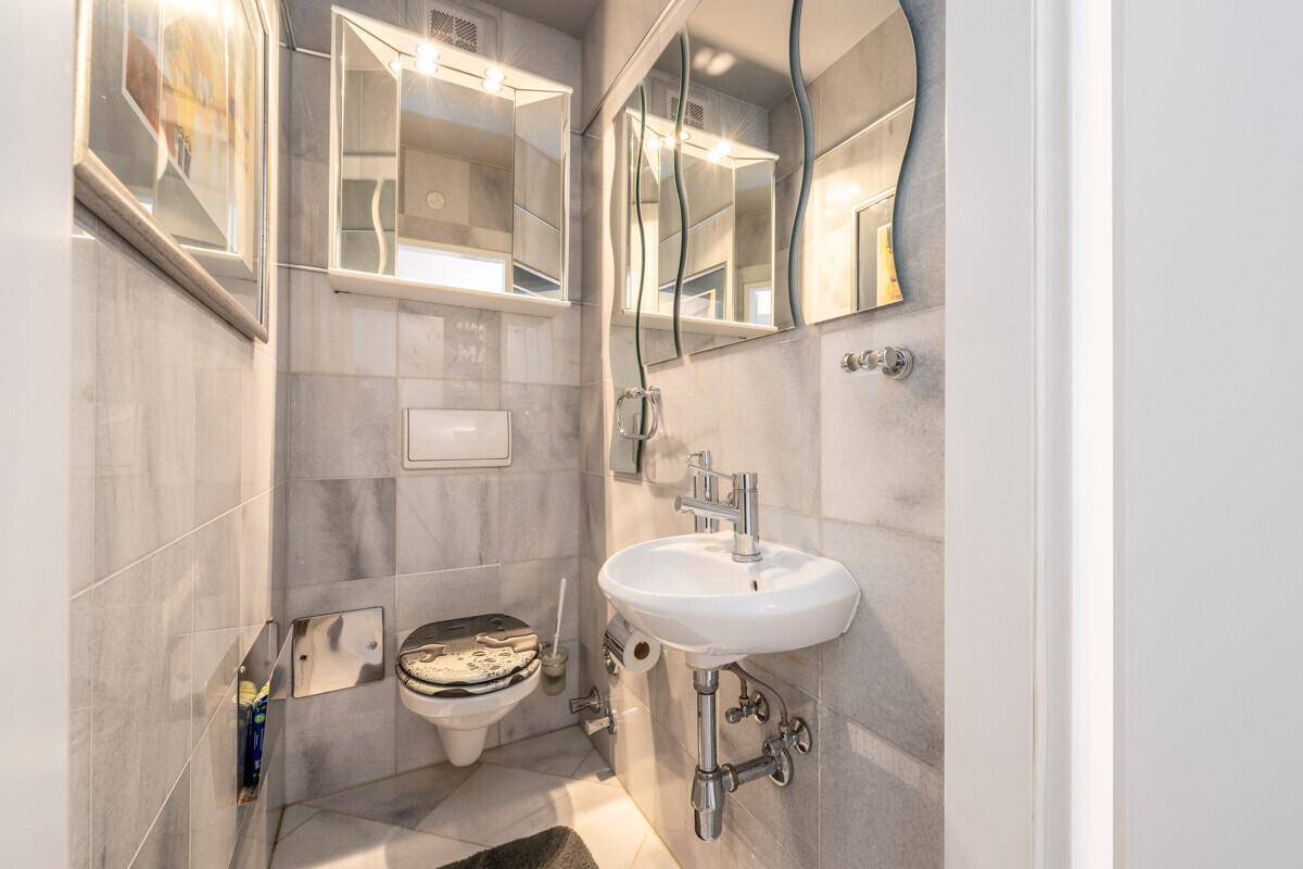Kleines Gäste-WC mit modernen grauen Fliesen, Wand-WC und einem Waschbecken.