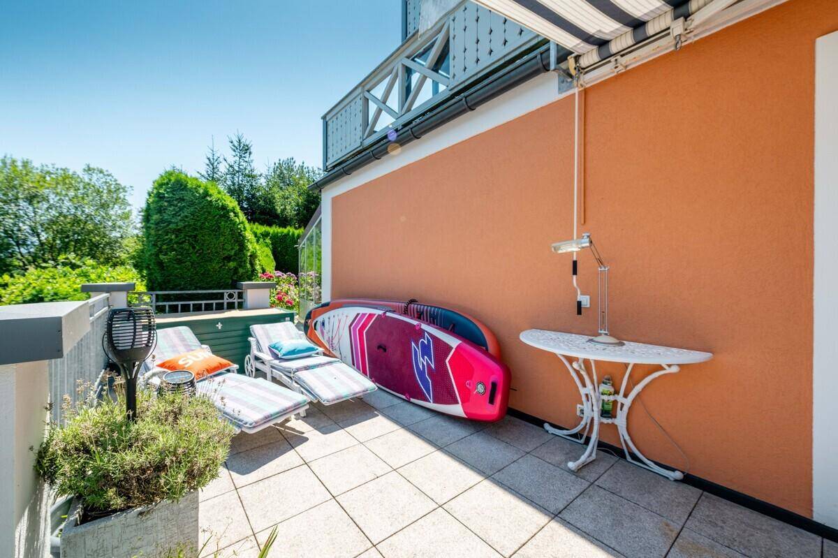 Sonniger Terrassenbereich mit Liegestühlen und Wassersportausrüstung, ideal zum Entspannen.