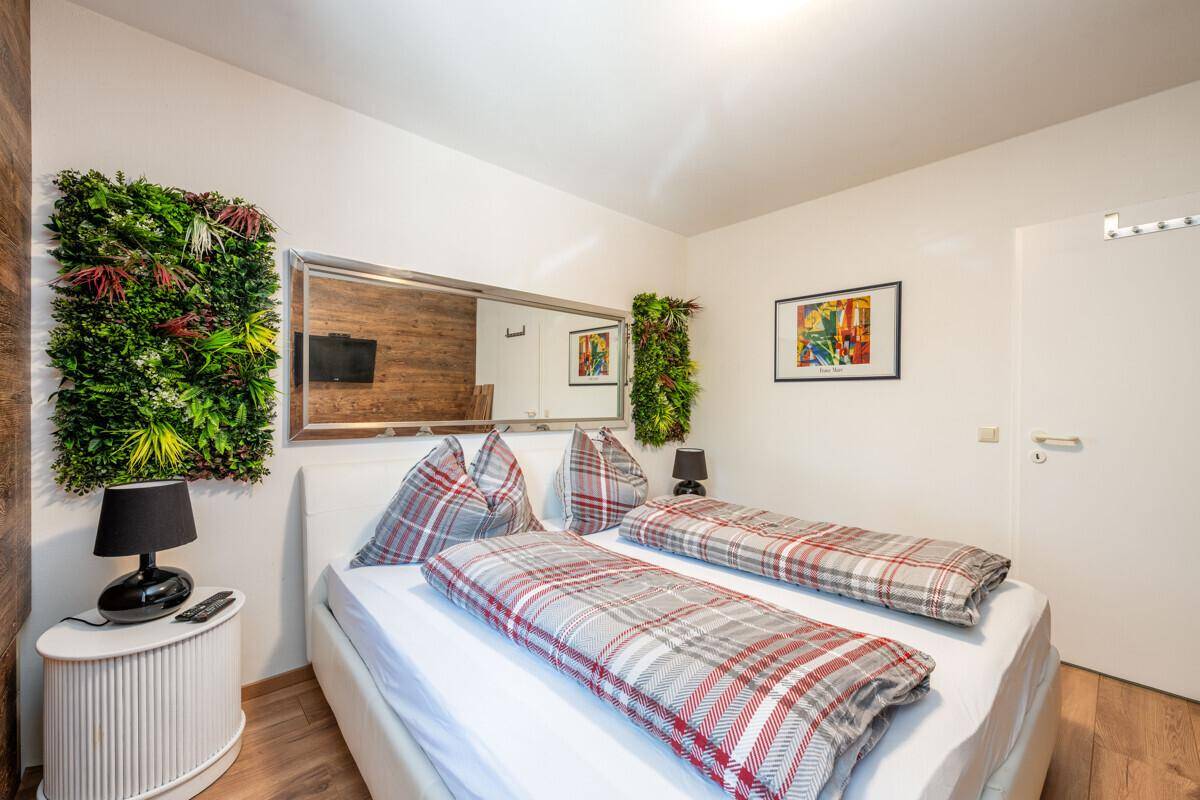 Schlafzimmer mit Holzwand, Doppelbett und moderner Kunst an der weißen Wand.