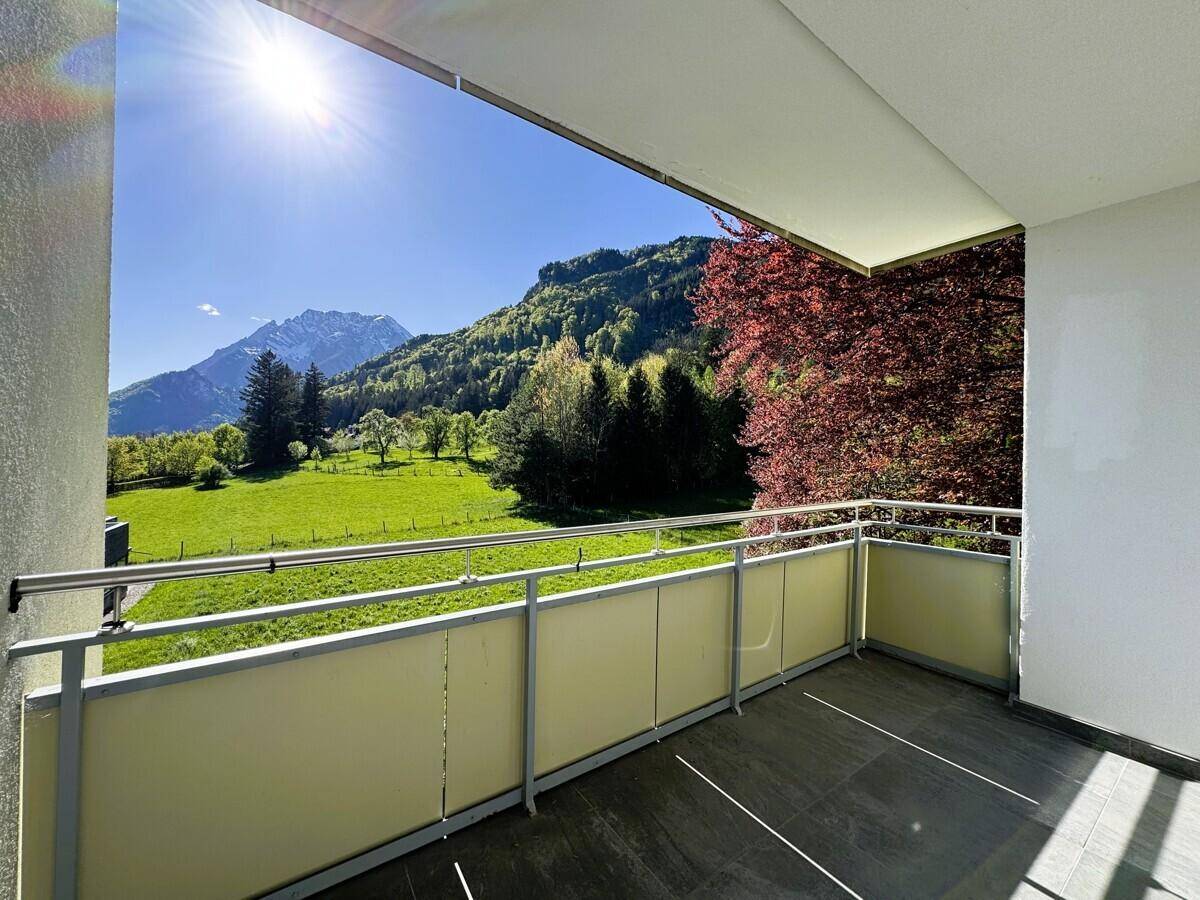 Sonniger Balkon mit atemberaubendem Panoramablick auf die Berge und grüne Wiesen.
