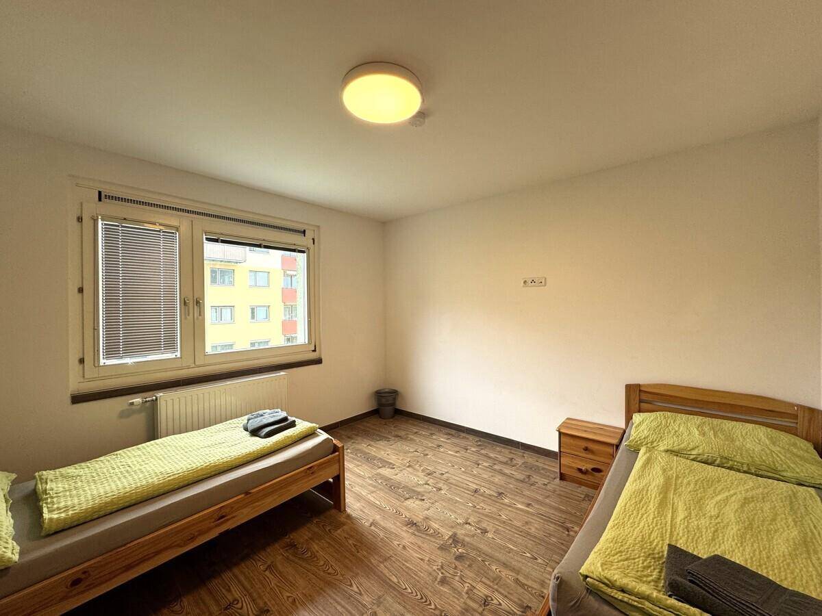 Schlafzimmer mit zwei Einzelbetten und Laminatboden, ideal für Gäste oder Kinder.