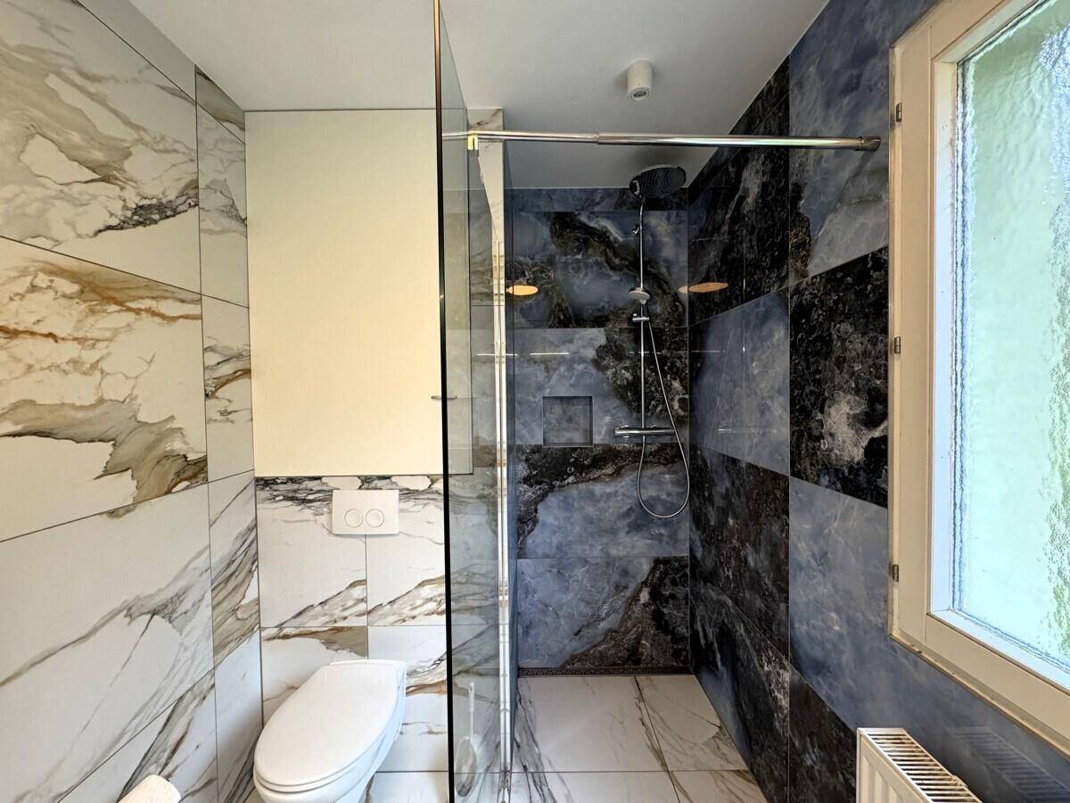 Elegantes Badezimmer mit begehbarer Dusche, wandhängendem WC und hochwertigen Marmorfliesen.