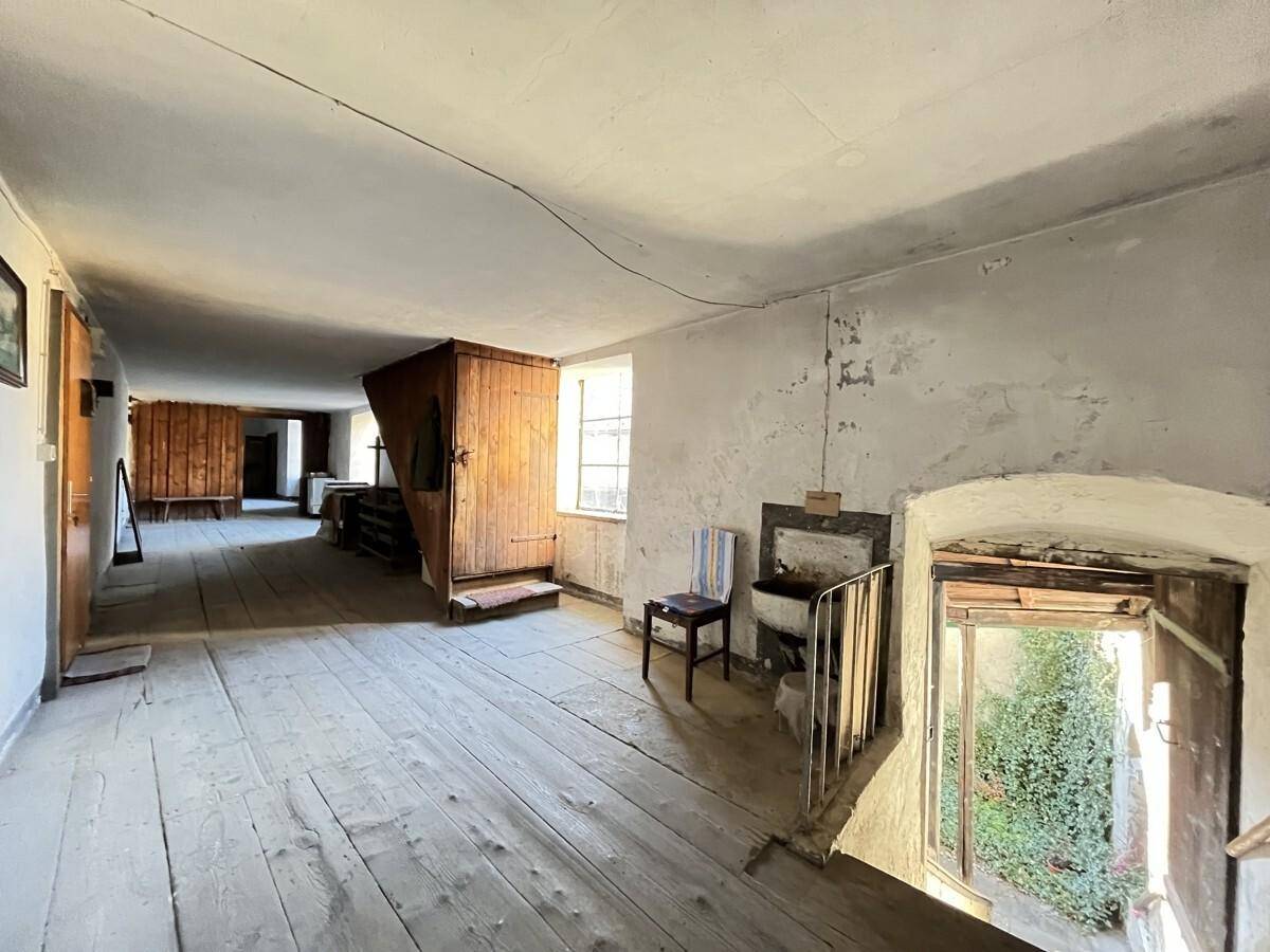 Großer Wohnraum mit Holzdielenboden, Blick in den Innenhof und rustikalen Holzelementen.
