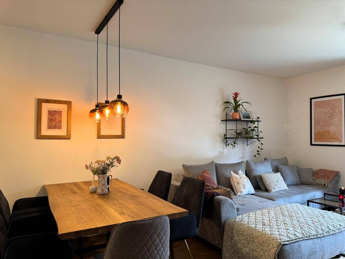 Gemütlicher Wohn- und Essbereich mit großem Ecksofa und modernem Holztisch.