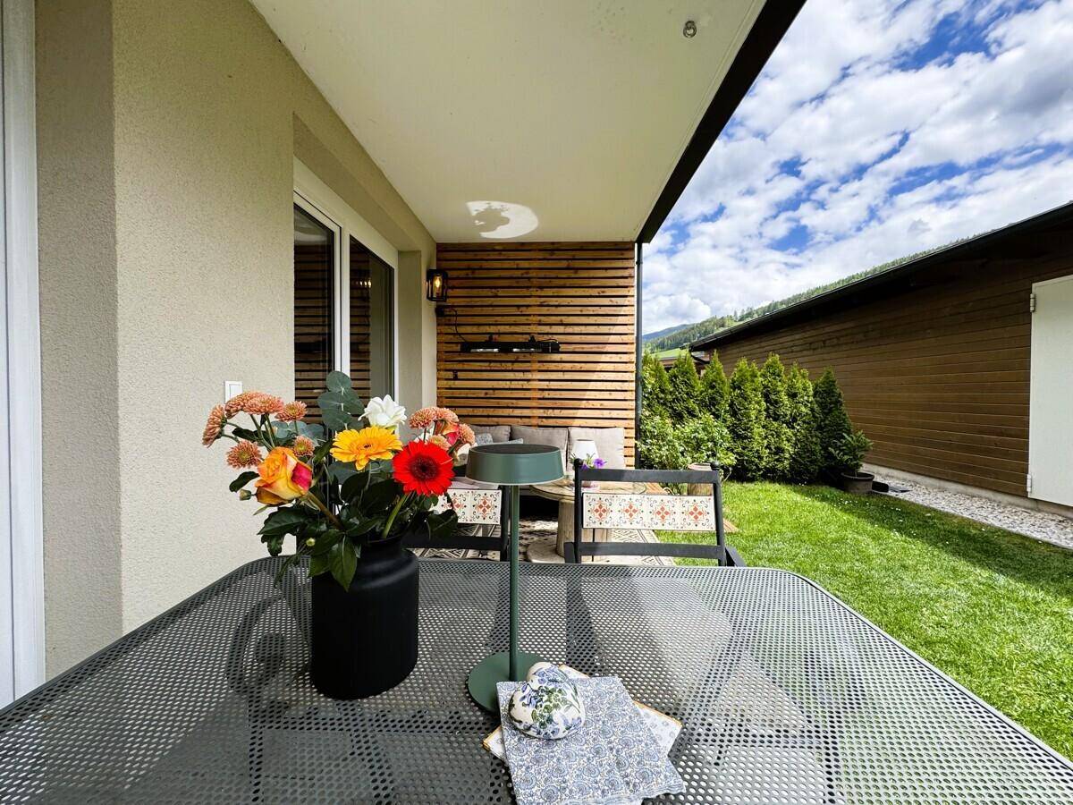 Detailaufnahme des Esstisches auf der Terrasse mit frischen Blumen und Bergblick.