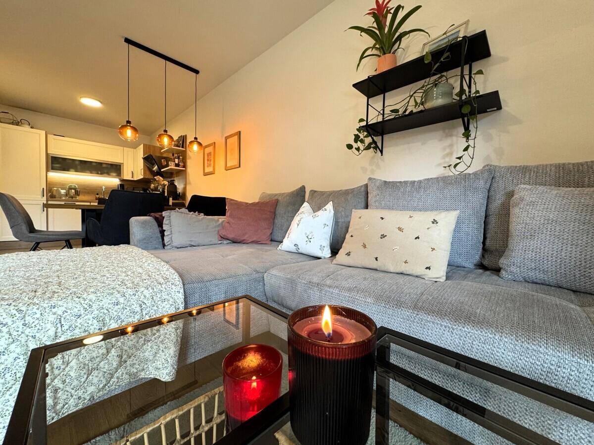 Offener Wohnbereich mit bequemer Couch und Blick auf die moderne Küche im Hintergrund.
