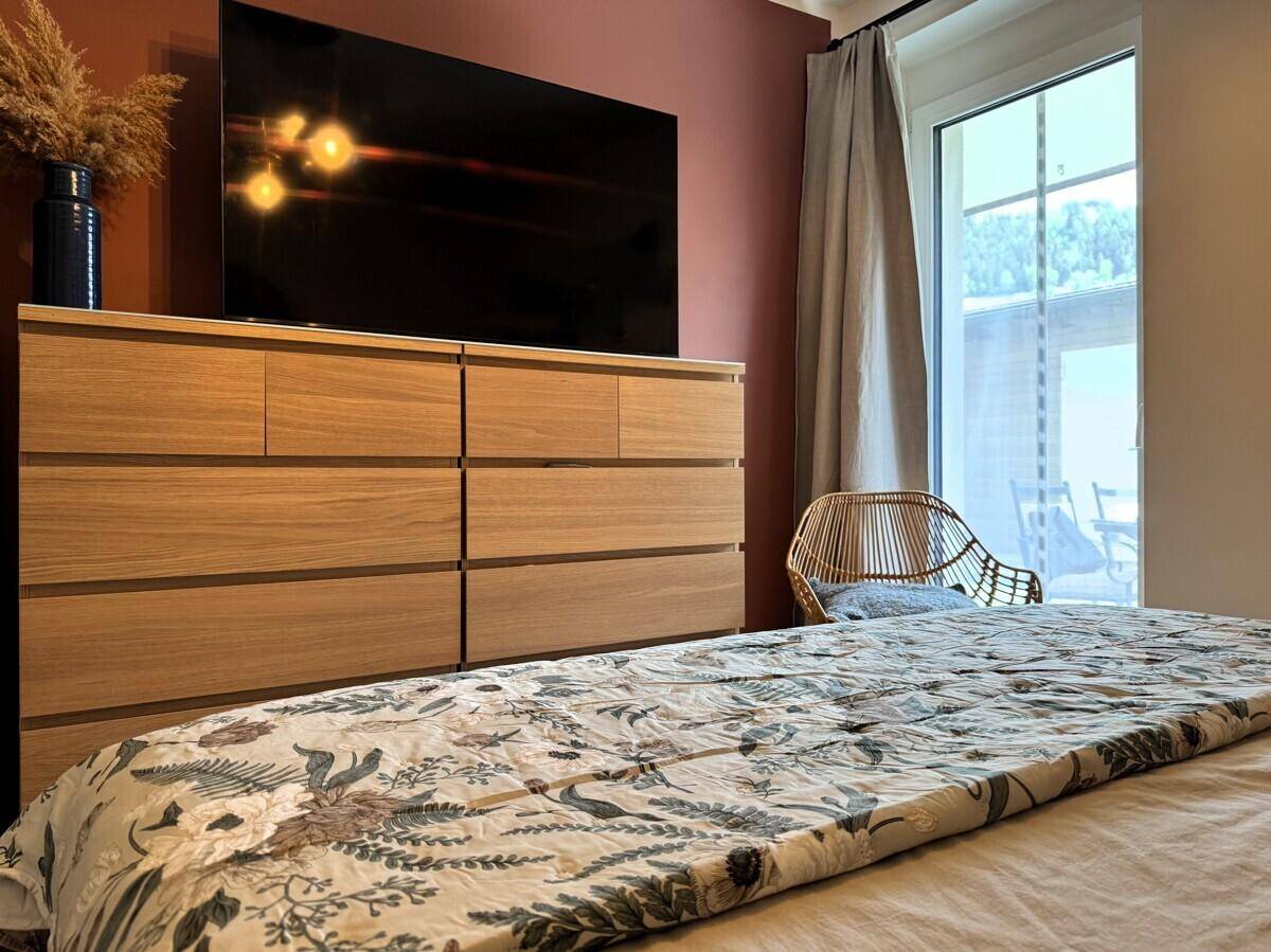 Gemütliches Schlafzimmer mit Holzkleiderschrank, großem Bett und Zugang zur Terrasse.