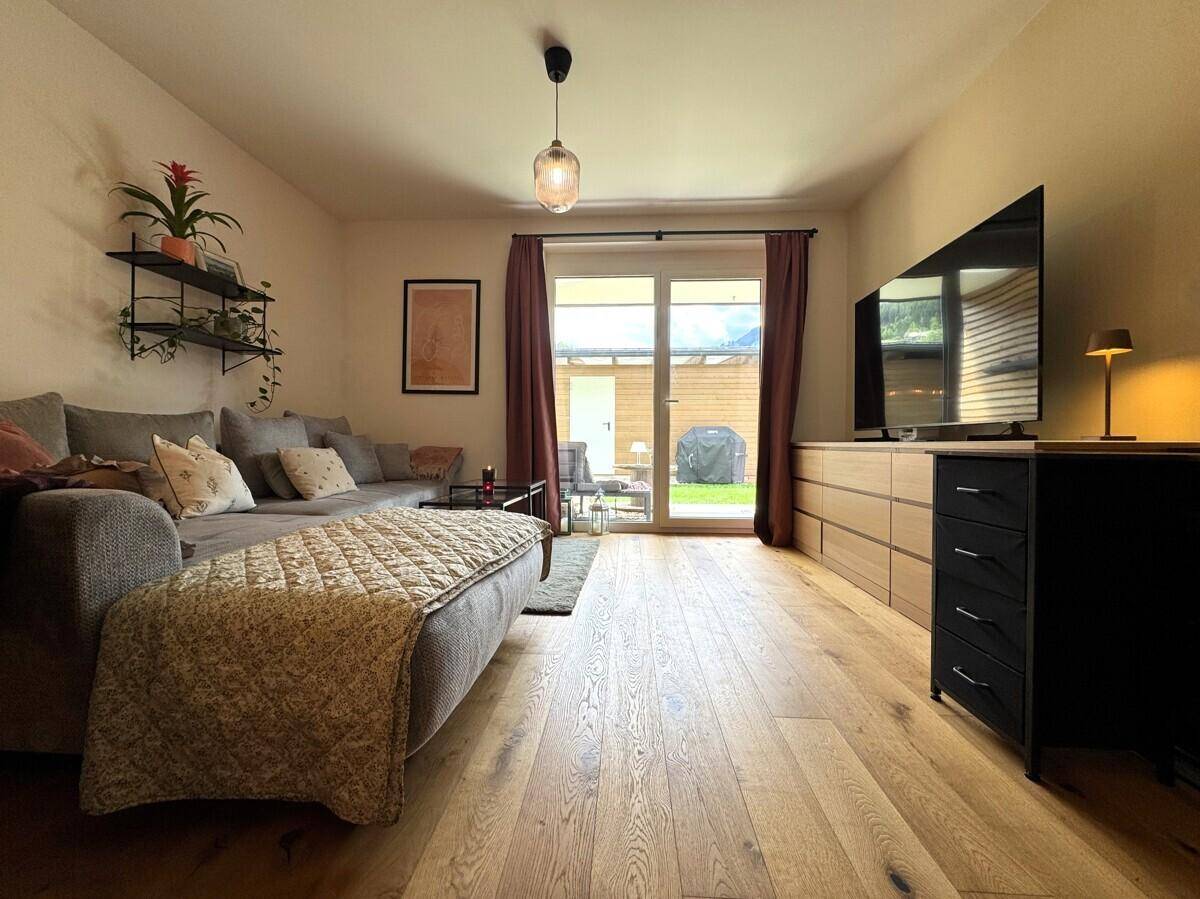 Geräumiges Wohnzimmer mit Holzboden, großem Sofa und Zugang zur Gartenterrasse.