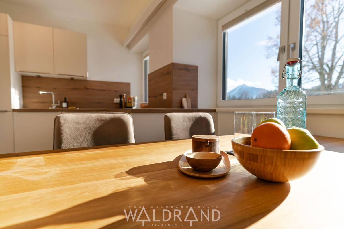 Esstisch mit Obstschale und Stühlen, mit Blick auf die Berge durch das Fenster.