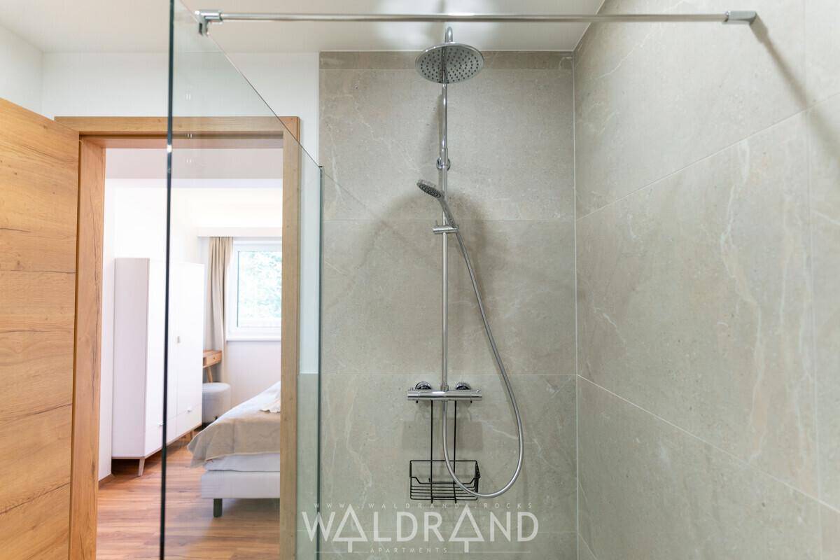 Moderne Dusche mit Regenduschkopf und Handbrause in einem elegant gefliesten Badezimmer.