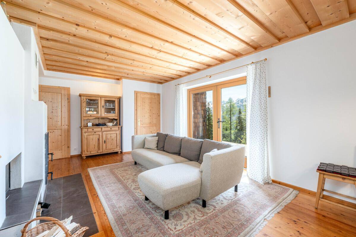 Heller Wohnbereich mit bequemer Couch, Holzbalkendecke und Zugang zu einem Balkon oder Terrasse.