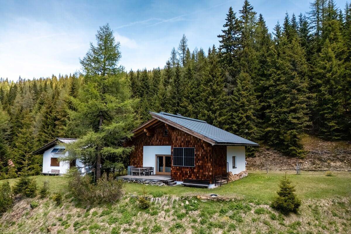 Charmantes Chalet mit Holzfassade und Satteldach, eingebettet in eine grüne Berglandschaft.