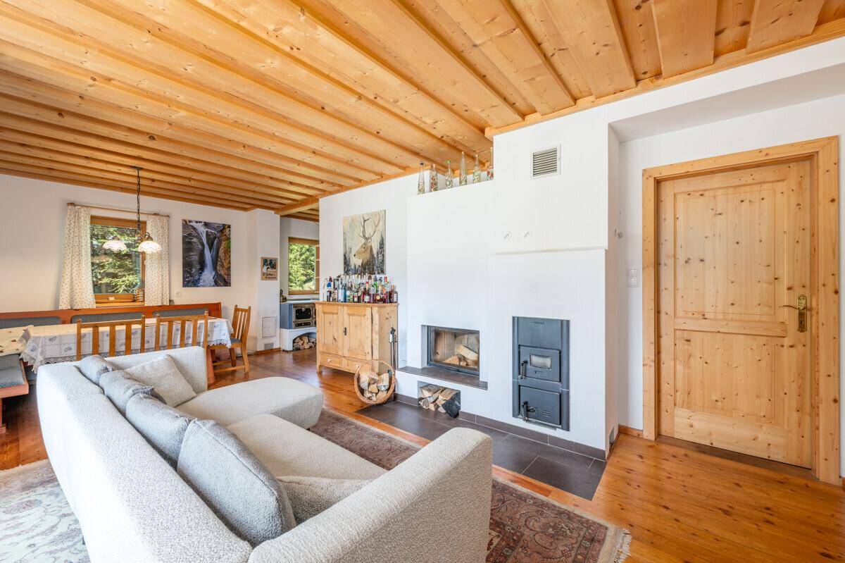 Gemütlicher Wohn-Essbereich im alpinen Stil mit Holzbalkendecke, Kamin und traditionellen Möbeln.