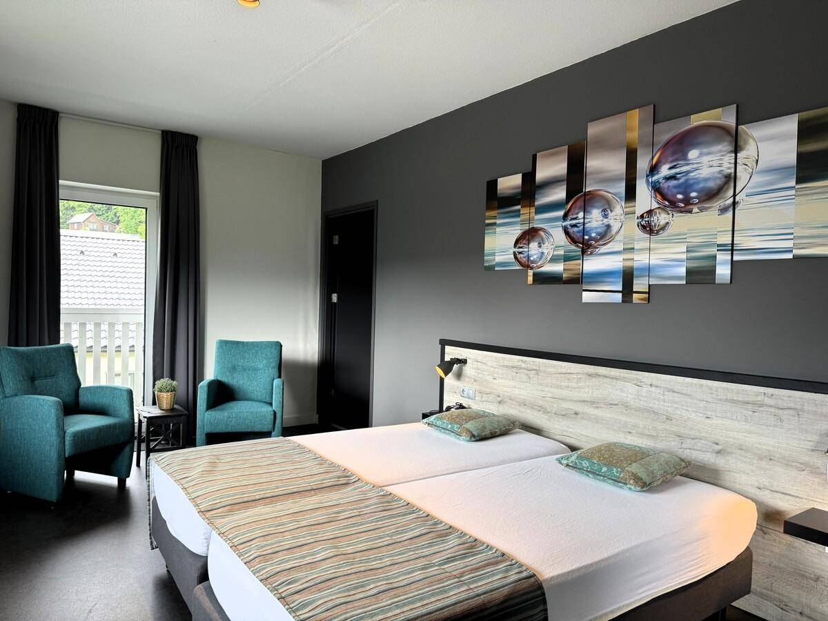 Gemütliches Schlafzimmer mit zwei Einzelbetten, bequemen Sesseln und direktem Zugang zum Balkon.
