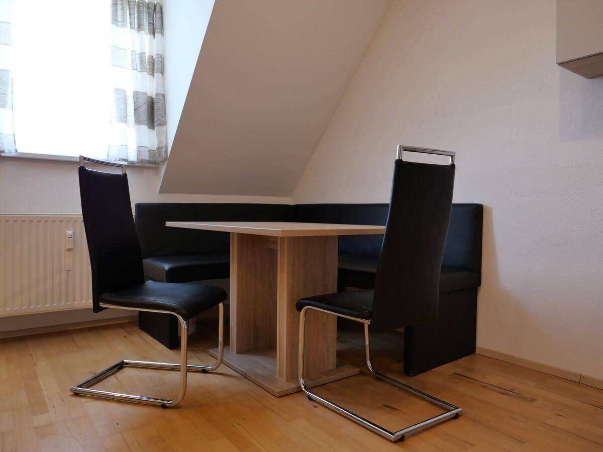 Gemütlicher Essbereich mit Eckbank und Holztisch unter der Dachschräge, ideal für Mahlzeiten.