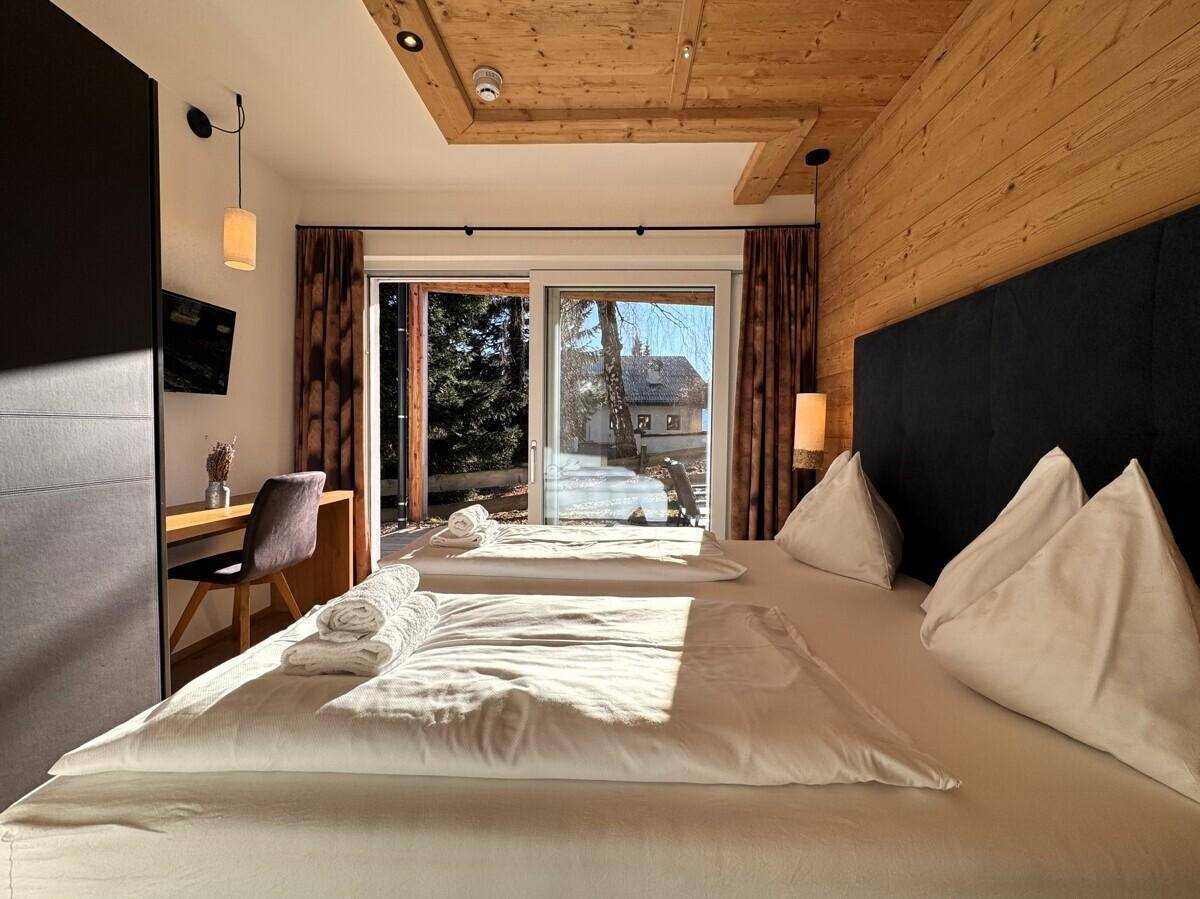 Gemütliches Schlafzimmer mit Doppelbett, Schreibtisch und großen Fenstern mit viel Tageslicht.