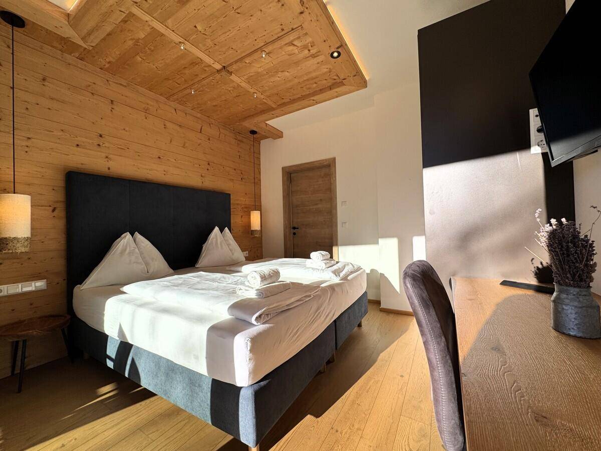 Helles Schlafzimmer mit Doppelbett, Schreibtisch und Holzwänden in modernem Design.