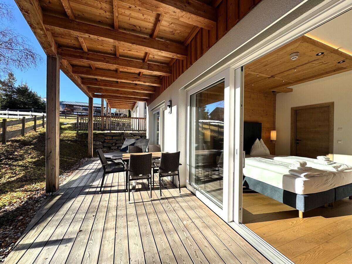 Geräumige Holzterrasse mit Esstisch und direktem Zugang zu einem Schlafzimmer.