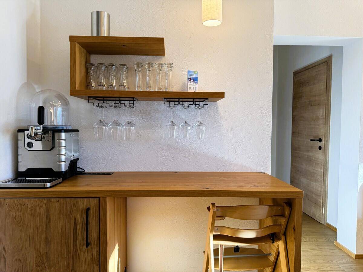 Gemütliche Bar-Ecke mit Holzregalen, Gläsern und einer Kaffeemaschine für gesellige Stunden.