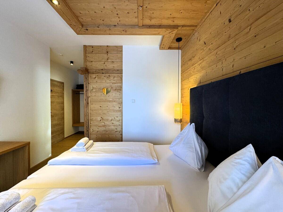 Gemütliches Schlafzimmer mit Doppelbett, Holzwänden und einem offenen Kleiderschrankbereich.