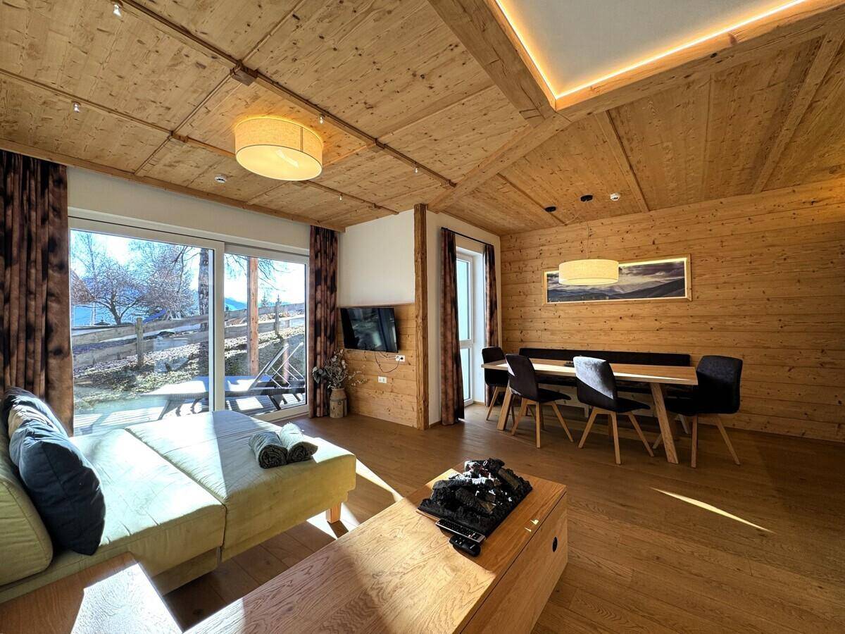 Geräumiger Wohn-Essbereich mit bequemer Couch, Fernseher und Zugang zur Terrasse.