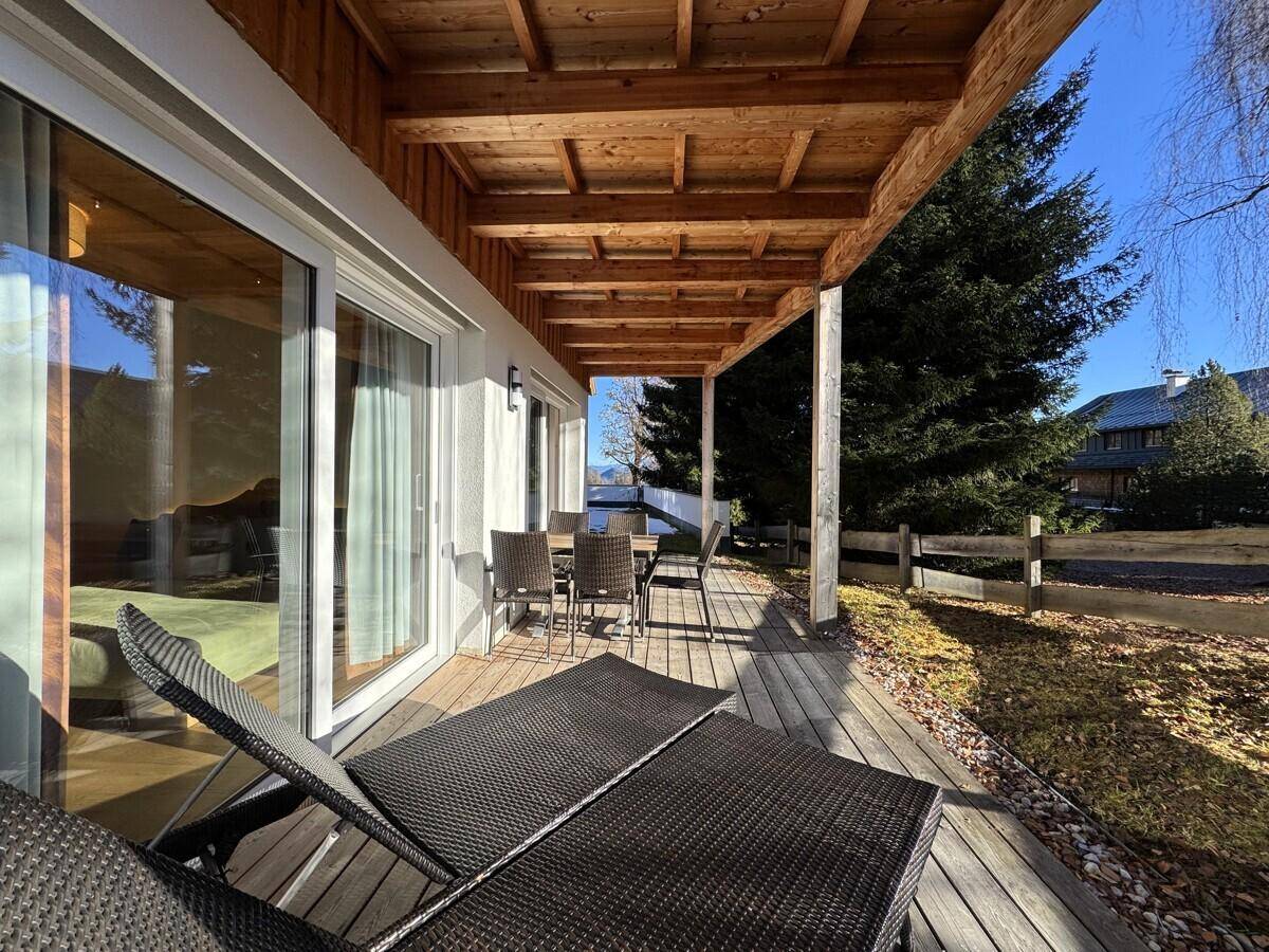 Geräumige Holzterrasse mit Sonnenliegen und Esstisch für entspannte Stunden im Freien.