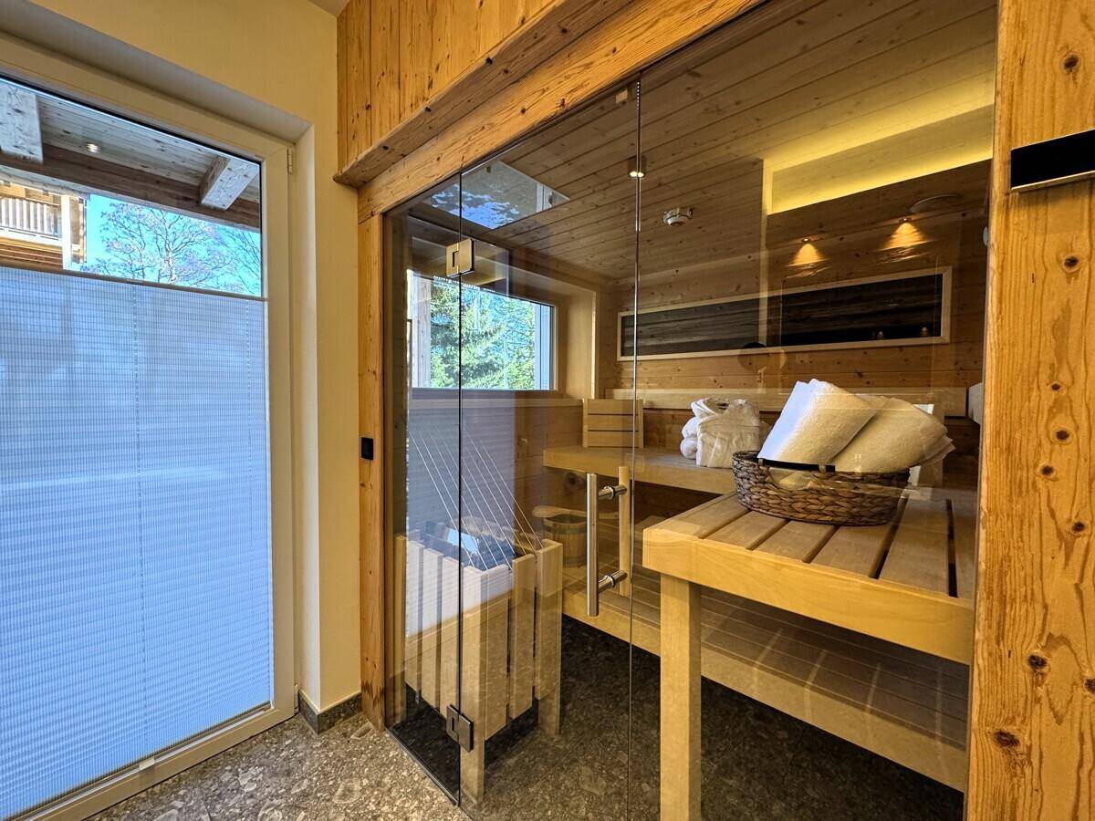 Moderne Sauna mit Holzausstattung, Glasfront und Blick ins Grüne für entspannende Momente.