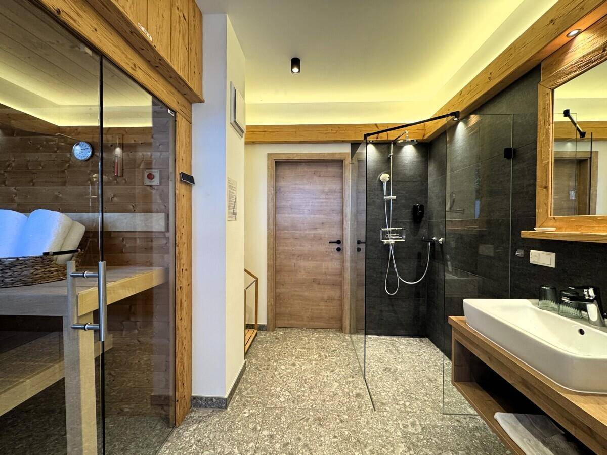 Modernes Badezimmer mit ebenerdiger Dusche, Waschbecken und integrierter Sauna.