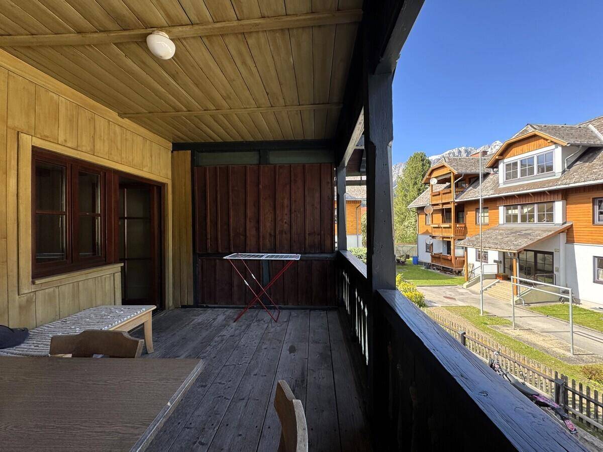 Überdachter Holzbalkon mit Sitzgelegenheiten und Blick auf die grüne Umgebung.