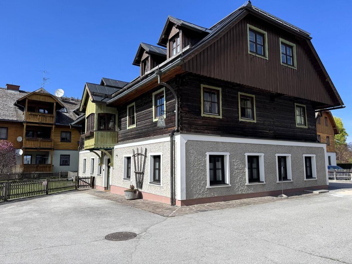 Traditionelles Gebäude mit Holzbalkonen und Satteldach in ländlicher Umgebung.