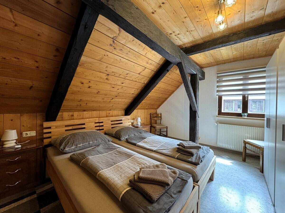 Helles Schlafzimmer mit Holzmöbeln, Dachschrägen und einem Fenster für Tageslicht.