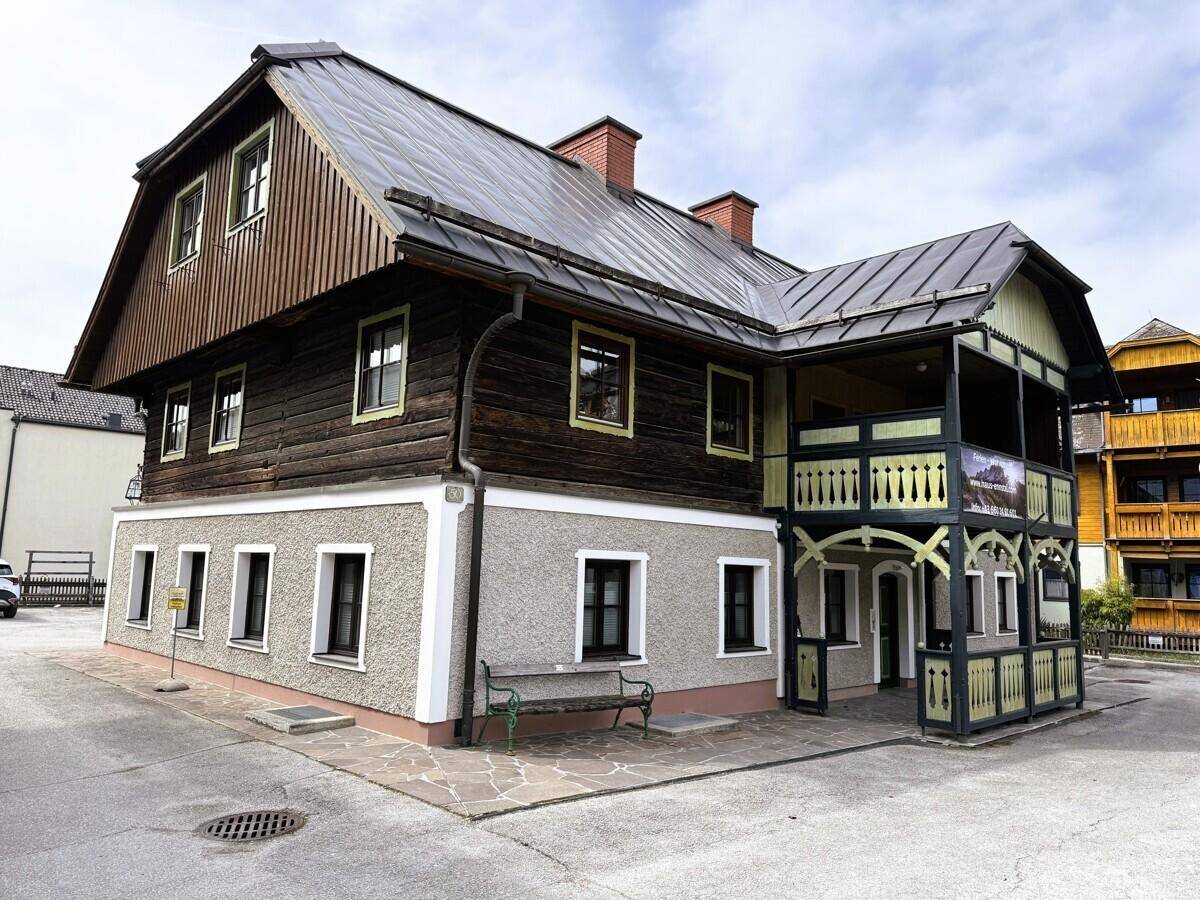 Traditionelles Gebäude mit Holzbalkonen und rustikaler Fassade in ländlicher Umgebung.