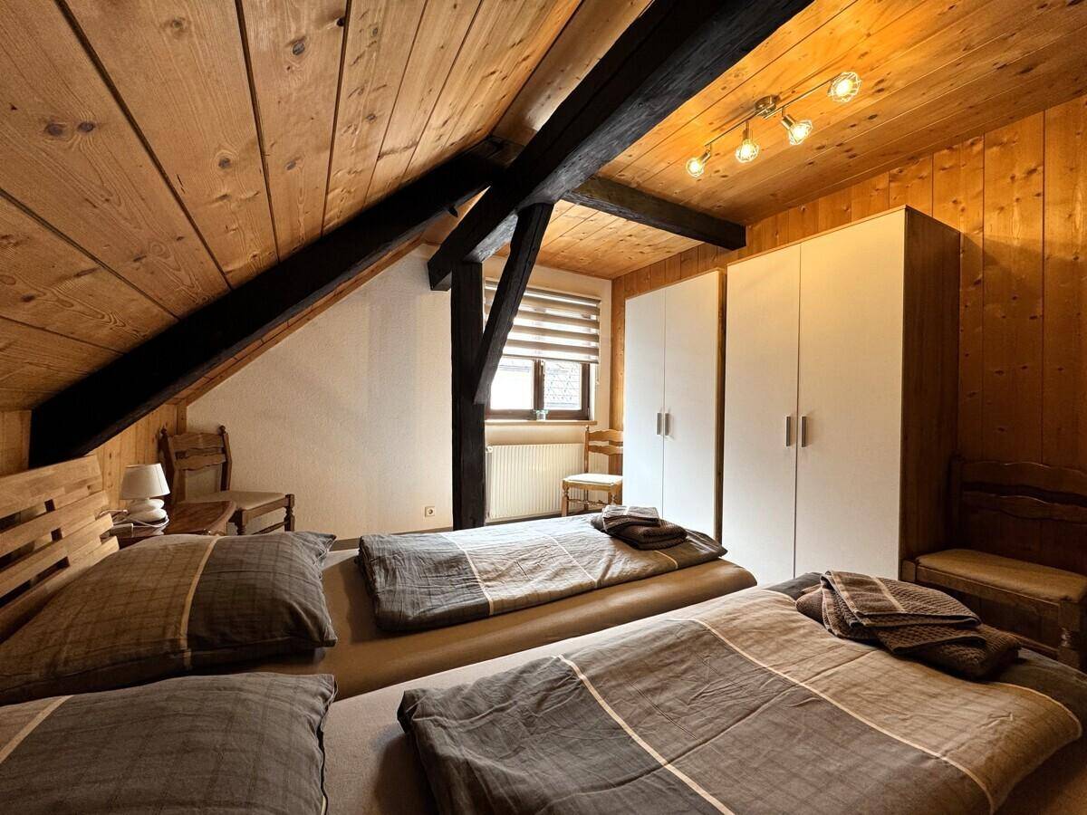 Gemütliches Schlafzimmer mit zwei Einzelbetten, Holzvertäfelung und Dachschrägen.
