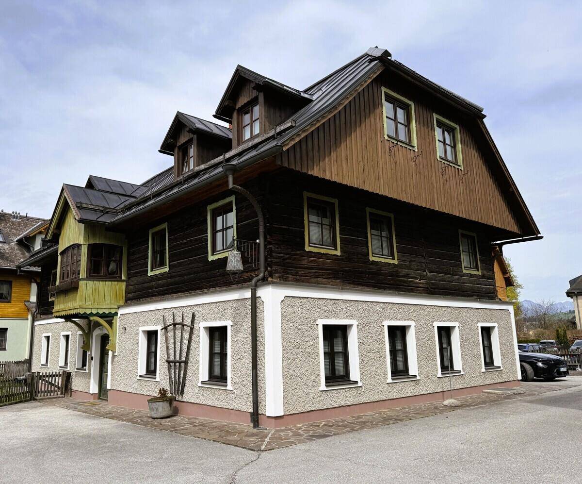 Rustikales Gebäude mit Holzfassade, Satteldach und traditionellen Fenstern.