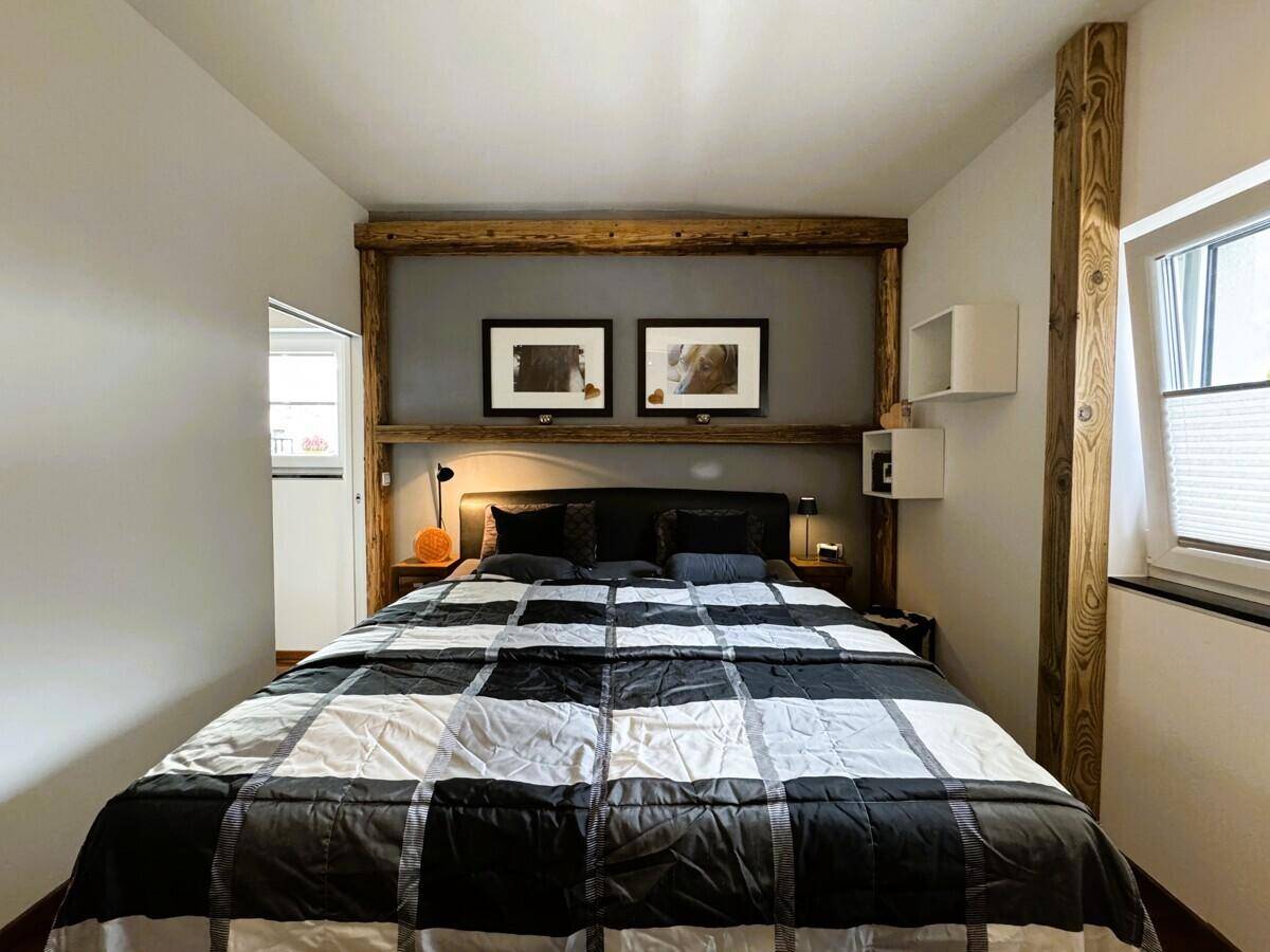 Schlafzimmer mit großem Bett, Holzbalken und schlichter, moderner Einrichtung.