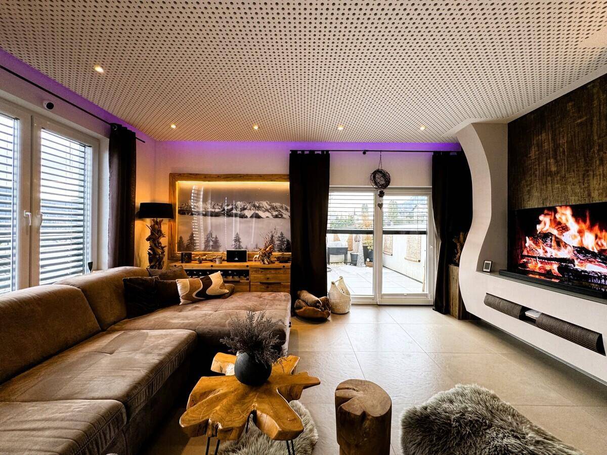 Modernes Wohnzimmer mit Kamin, großem Sofa und indirekter Beleuchtung für gemütliche Abende.
